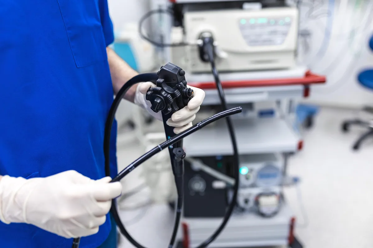 Medic prezentând un colonoscop - echipamentul folosit pentru screening-ul cancerului de colon